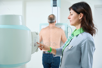 Doctor operating X-ray machine while standing attain the patient