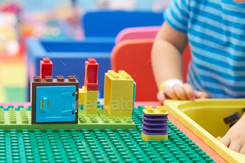 tiny one taking part in and building with vibrant plastic bricks desk. Early learning and pattern.