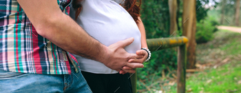 Female pregnant and her accomplice maintaining belly on nature