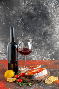 entrance ogle new fish slices with tomatoes wine and lemon slices on darkish background portray dish color