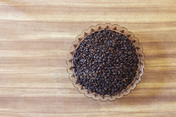 High behold of espresso beans in a bowl on a wood background