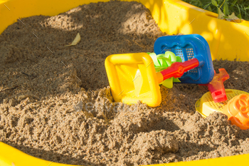 standing of colored plastic toys on the sand, kid’s sandbox in summer season Sunny day