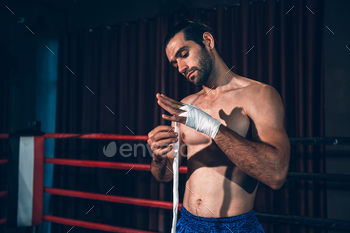 Boxing athlete men wrapping hand with boxing tape sooner than wearing boxing gloves at health club.