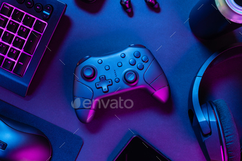 Game controller with pink lit keyboard amidst diverse wireless devices