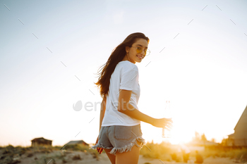 Honest lady ingesting beer at the seaside at sunset. Young lady having fun with on seaside holiday. Summertime