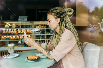 Young girl sits in cafe and drinks cappuccino.