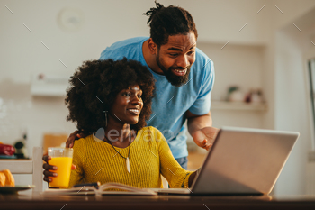 A elated african american woman is showing a mission to her supportive husband who is hugging her.