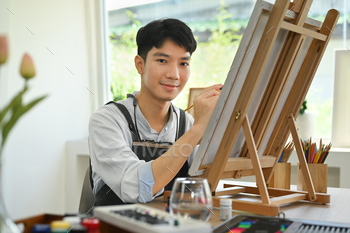 Heavenly male artist painting with watercolor on canvas at home studio workshop.