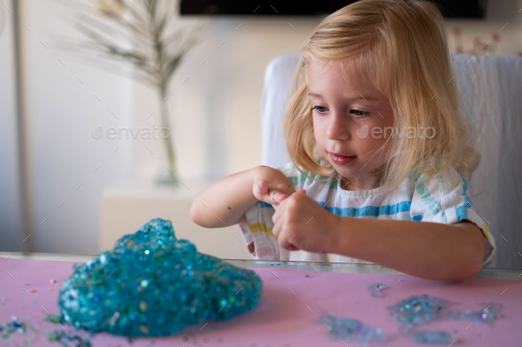 Cute toddler twiddling with lustrous slime indoors. Leisure process for cramped one, messy video games thought