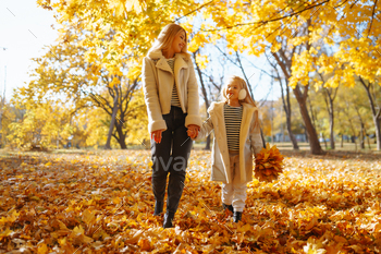 Chuffed mother and daughter comprise stress-free in autumn park at sundown. Family on hotfoot. Childhood, walks, rest.