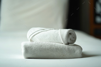 Halt up and selective focal level white roll towels on a bed at hotel.