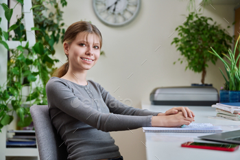 Portrait of stripling lady sitting at desk at home with pc