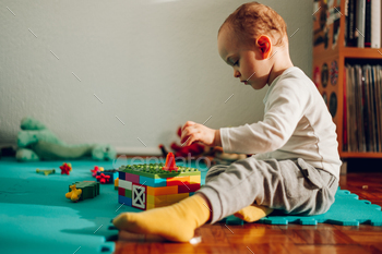 Facet see of a adorable diminutive boy provocative himself and playing a relaxing sport with plastic bricks.