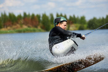 Movement shot teen with disability wakeboarding on water