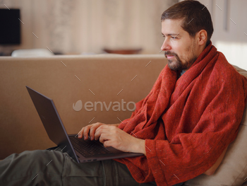 Unwell man lined in heat blanket  laptop laptop cloak cloak