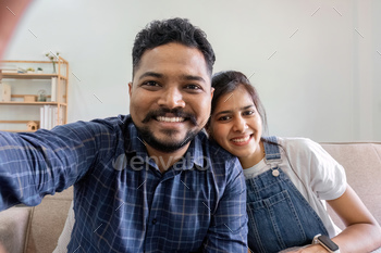 Couple taking selfies whereas sitting within the lounge.