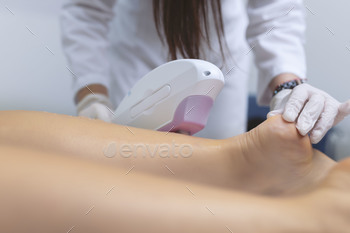 Beautician removes hair on comely feminine legs using a laser.