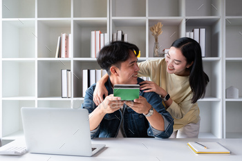 Chuffed Asian couple smiling They checked out every diverse and held the legend e book, having a glance on the