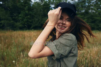 lady straightens her cap on her head and green shirt nature unique air