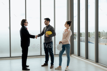 Engineer workers handshake after meeting to see the explain blueprint drawings, work thought