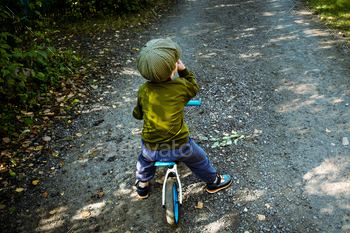 Active toddler boy rides on steadiness bike alongside course.