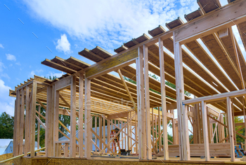 Narrate work in development viewing an unfinished home with wood framing beams