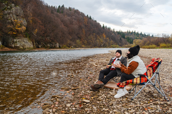 pleased couple having picnic at river beach