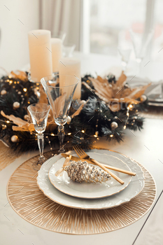 Christmas table surroundings and luxury decoration in gold colors. Festive and trim golden dwelling decor