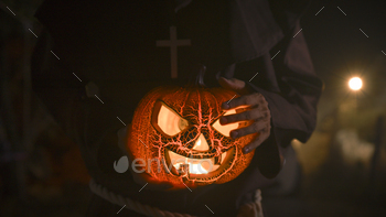 Monk holds a Halloween Pumpkin In a Darkish Night