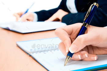 Cropped image of hand of young lady taking notes