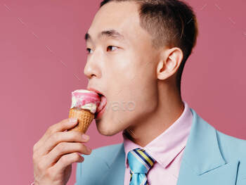 A person of Korean appearance in a suit on a crimson background and a appetizing ice cream in his hand