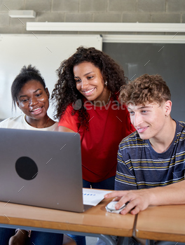 Community of multiracial student mates sharing a computer at some stage in class to offer an assignment.