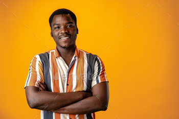 Portrait of smiling young african man in striped shirt towards orange background