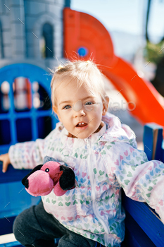 Diminutive smiling woman sitting on a bench throughout the playground