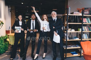 Workforce of elated colleagues standing in workplace