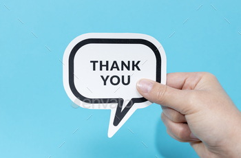 Hand retaining a speech bubble with message Thank You isolated on blue background