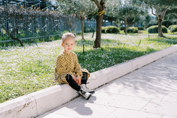 Runt smiling woman sits on the curb strategy a flowering meadow