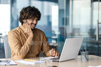 Determined islamic man touching cheek with hand and squinting ensuing from extreme toothache by desk with