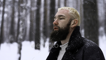 Man stress-free within the cool local weather woodland, the opinion of unity with nature. Media. Younger blond man pondering