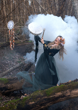 Wild Woman Participating in Shamanic Drum Standing On Inexperienced Moss Tree Trunk In Forest, White Smoke Bomb