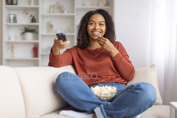 Snug shadowy woman taking half in film night at dwelling, spirited popcorn