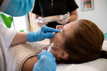 Magnificence specialist making use of magnificence product with syringe on face of shopper in sanatorium