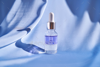 Two-part facial serum on a blue silk background.