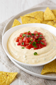 Do-it-yourself tacky dip in a bowl, yellow tortilla chips, facet stare. Closeup.