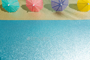 Summary seashore with glitter paper sand and water and cocktail umbrellas