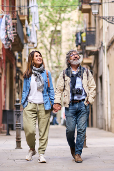 Overjoyed grownup Caucasian couple strolling preserving hand exterior. Feeble marriage looking out a bit smiling.