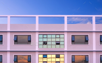 Up to date area of labor constructing with sunset sky reflection on many glass dwelling home windows floor in opposition to blue sky