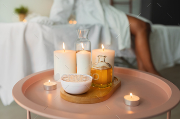 Candles and therapeutic massage oil on a crimson desk