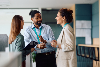 Dim businessman speaking to female coworker whereas working within the place of job.