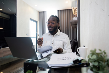 African American man working with pocket book pc laptop faraway whereas sitting at glass desk in residing